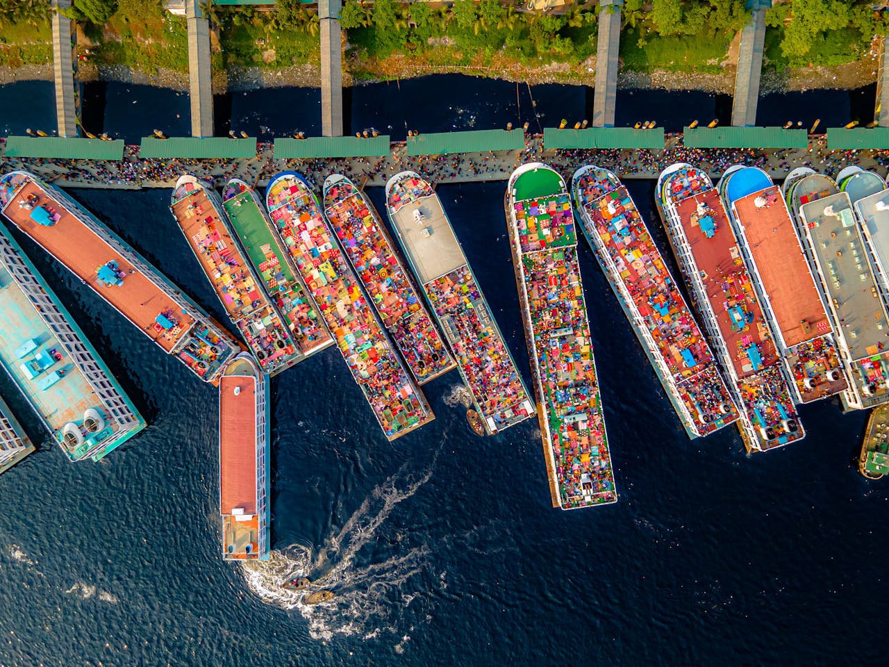 A vibrant aerial shot of numerous colorful boats docked at a bustling port, showcasing vivid market activity.
